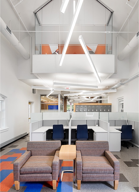 A workspace with several desks and two lounge chairs.