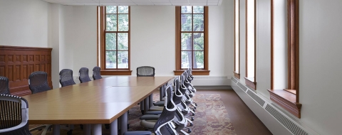 A room with a long table and 12 chairs.